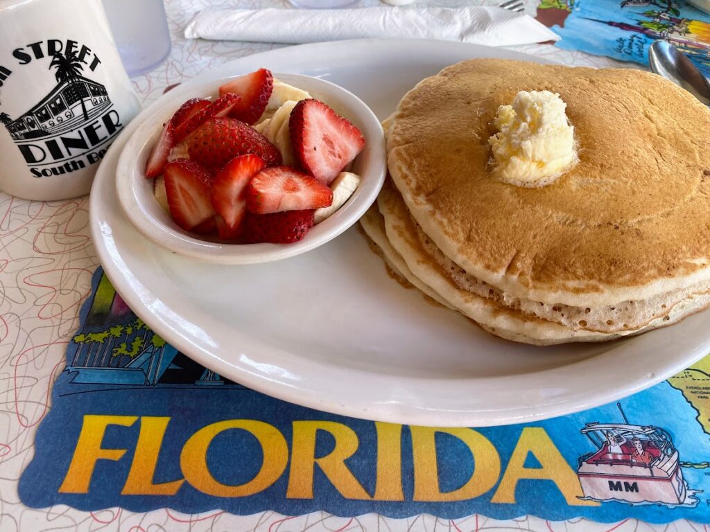 foto di un piatto di pancake con accanto una ciotolina di fragole Tutto su una tovaglietta con scritto Florida