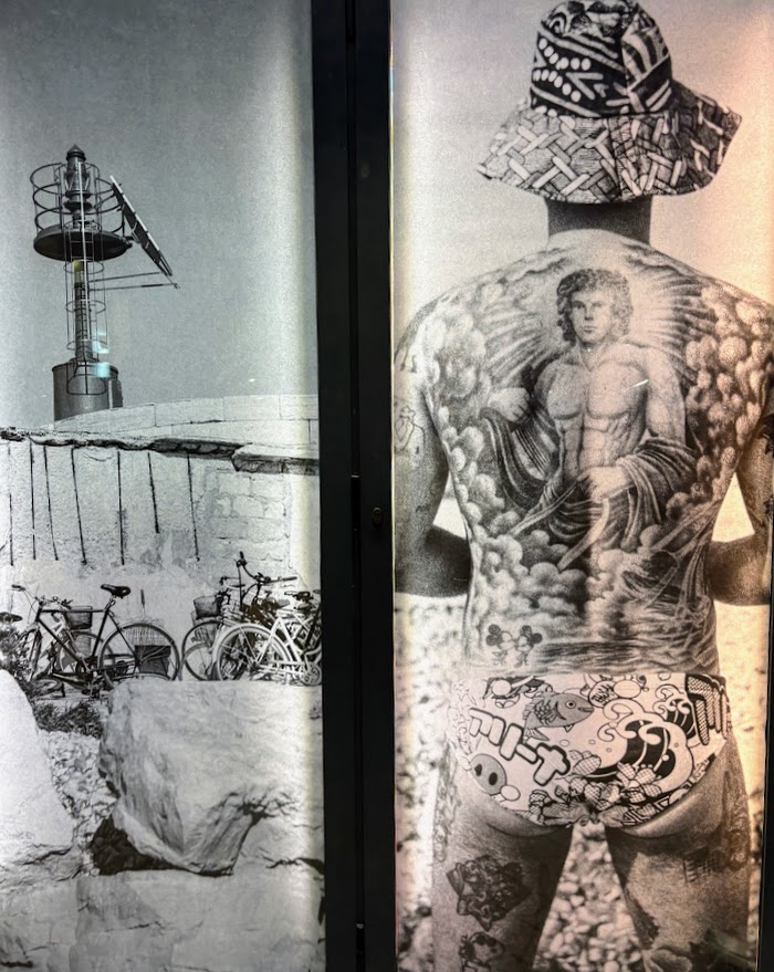 uomo tutto tatuato in costume fotografato di spalle vicino al mare